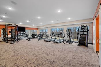 a gym with treadmills and weights in a room with windows